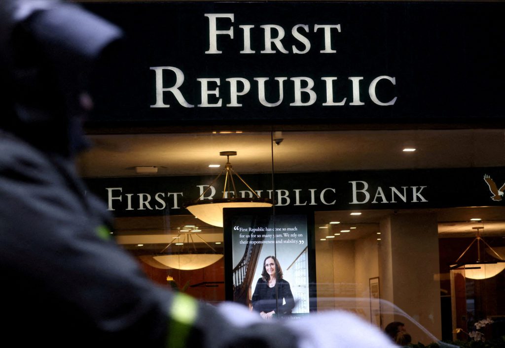 Fachada do banco First Republic com seus letreiros e display interno. Uma pessoa observa em primeiro plano.