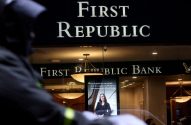 Fachada do banco First Republic com seus letreiros e display interno. Uma pessoa observa em primeiro plano.