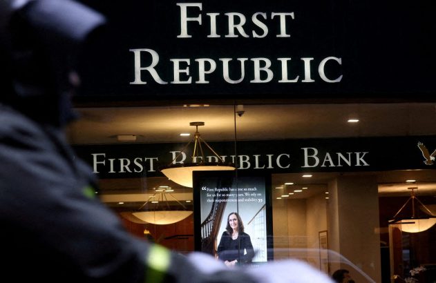 Fachada do banco First Republic com seus letreiros e display interno. Uma pessoa observa em primeiro plano.