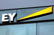 Sinal da EY com letras brancas e barra amarela vibrante em prédio moderno.