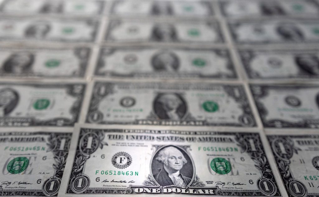 Cédulas de um dólar americano dispostas em grade, com foco nas da frente e as de trás borradas.