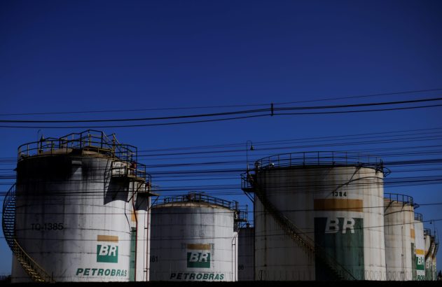 Tanques industriais da Petrobras com logos BR e fios elétricos sob céu azul.