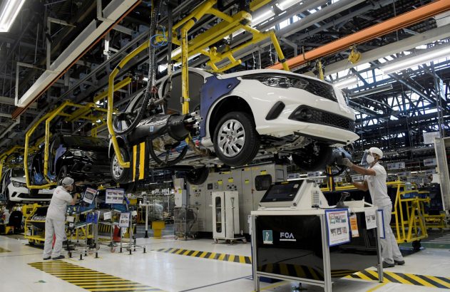 Linha de montagem de carros: trabalhadores montam veículos brancos suspensos. Fábrica FCA.