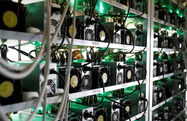 Racks com equipamentos eletrônicos em funcionamento, iluminados por luz verde.