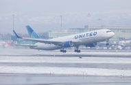 Avião da United Airlines decolando em aeroporto coberto de neve e céu nublado.