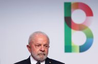 Presidente Lula com olhar sério; atrás, logo "B" multicolorido em fundo branco.