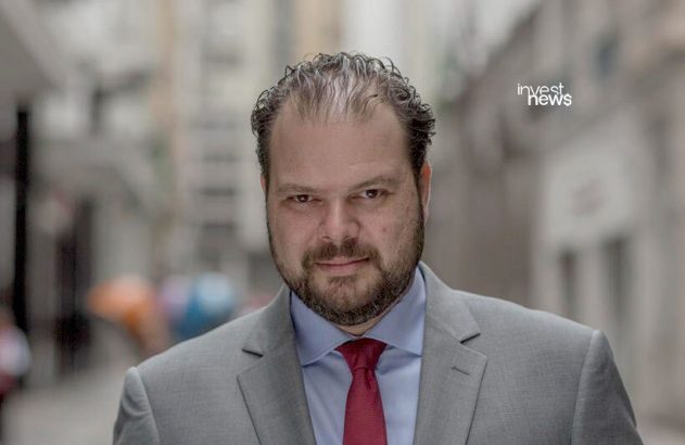 Mãos seguram tablet com robôs industriais e painel de controle em fábrica.