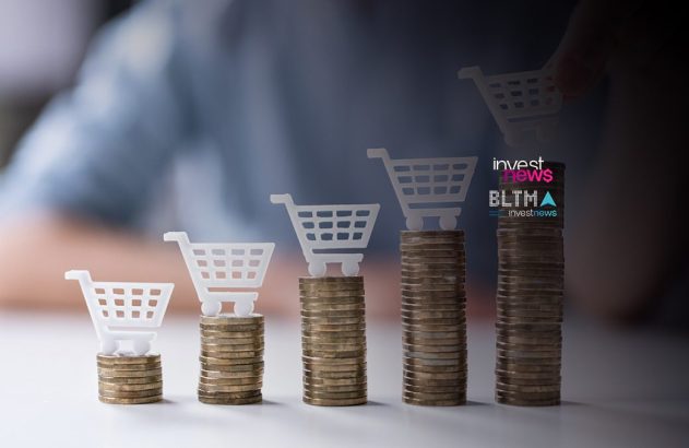 Pilhas de moedas crescentes com carrinhos de compra acima. Uma mão adiciona um carrinho à maior pilha.