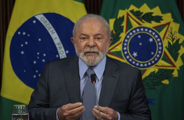 Lula discursa, com bandeiras do Brasil e o brasão nacional ao fundo.