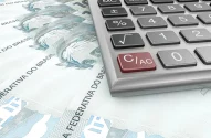cédulas de 100 reais ao lado de uma calculadora