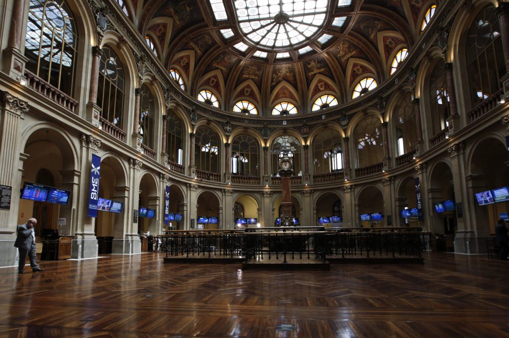 Vasto salão circular de bolsa de valores com piso de madeira, cúpula no teto e uma pessoa solitária.