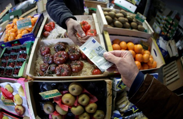 Mão oferece 5 euros por frutas e vegetais frescos em barraca de feira.