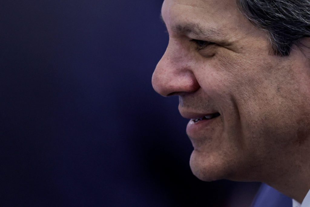 Homem em perfil, sorrindo e olhando para a esquerda. Fundo azul-escuro.