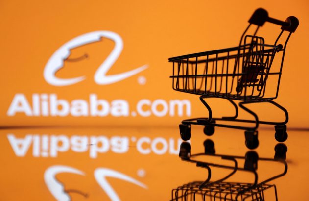 Carrinho de compras miniatura com logo Alibaba.com em fundo laranja reflexivo.