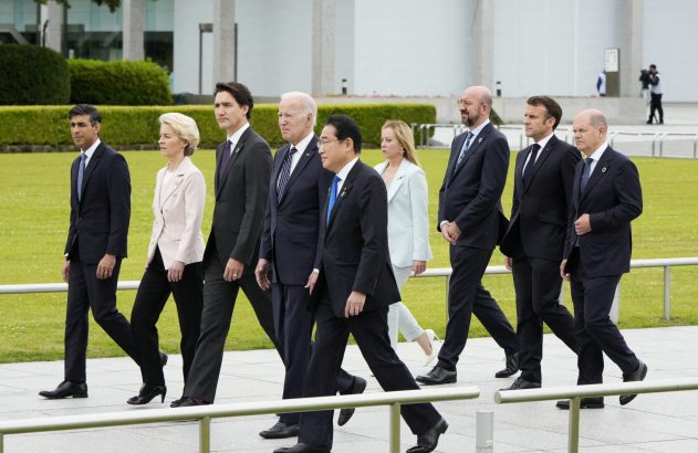 Líderes do G7 caminham em grupo por um caminho ao ar livre durante uma cúpula.