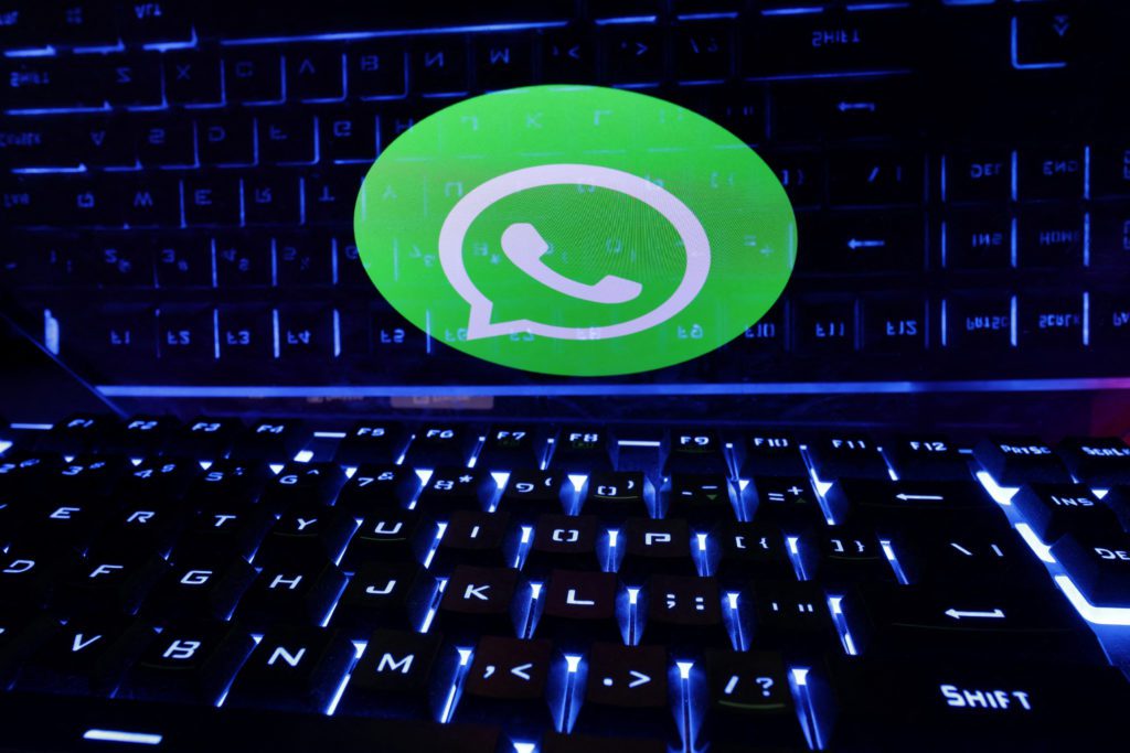 Logotipo do WhatsApp em destaque sobre um teclado de computador com retroiluminação azul.