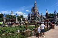 Castelo da Cinderela em parque Disney, com visitantes em frente em dia de sol.