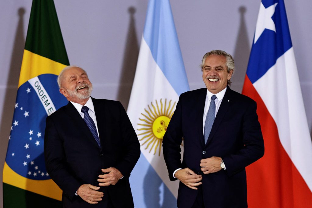Lula rindo e Fernández sorrindo. Bandeiras de Brasil, Argentina e Chile atrás.
