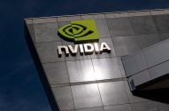 O logotipo da Nvidia em verde e o nome "NVIDIA" em letras metálicas no prédio, sob um céu azul.