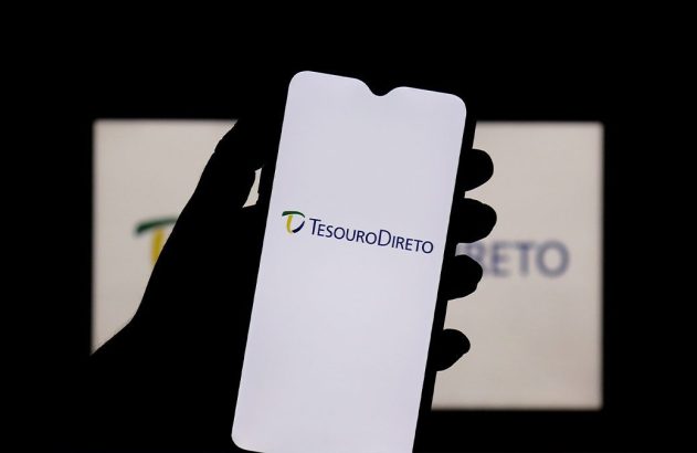 Mão segura celular com app Tesouro Direto. Ao fundo, logo do Tesouro Direto em tela.