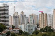 Vista aérea de uma cidade com inúmeros arranha-céus, vegetação esparsa e céu cinzento.