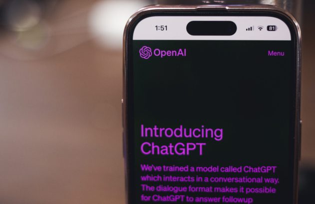 Um smartphone exibe a página de introdução do ChatGPT da OpenAI, com texto em roxo em fundo escuro.