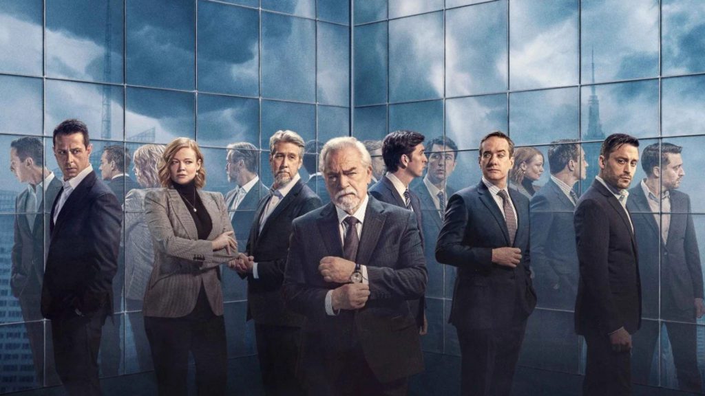 Elenco de Succession em ternos, Logan Roy ao centro, cercado por figuras borradas em prédio espelhado.