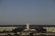 Vista panorâmica do Congresso Nacional em Brasília, Brasil, e edifícios verdes sob céu claro.