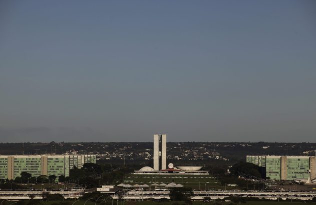 Vista panorâmica do Congresso Nacional em Brasília, Brasil, e edifícios verdes sob céu claro.