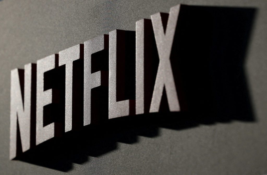 Nome Netflix em letras 3D anguladas, com sombras longas em relevo, sobre superfície escura.