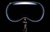 Homem apresenta óculos VR/AR grande e espelhado, suspenso em fundo preto.