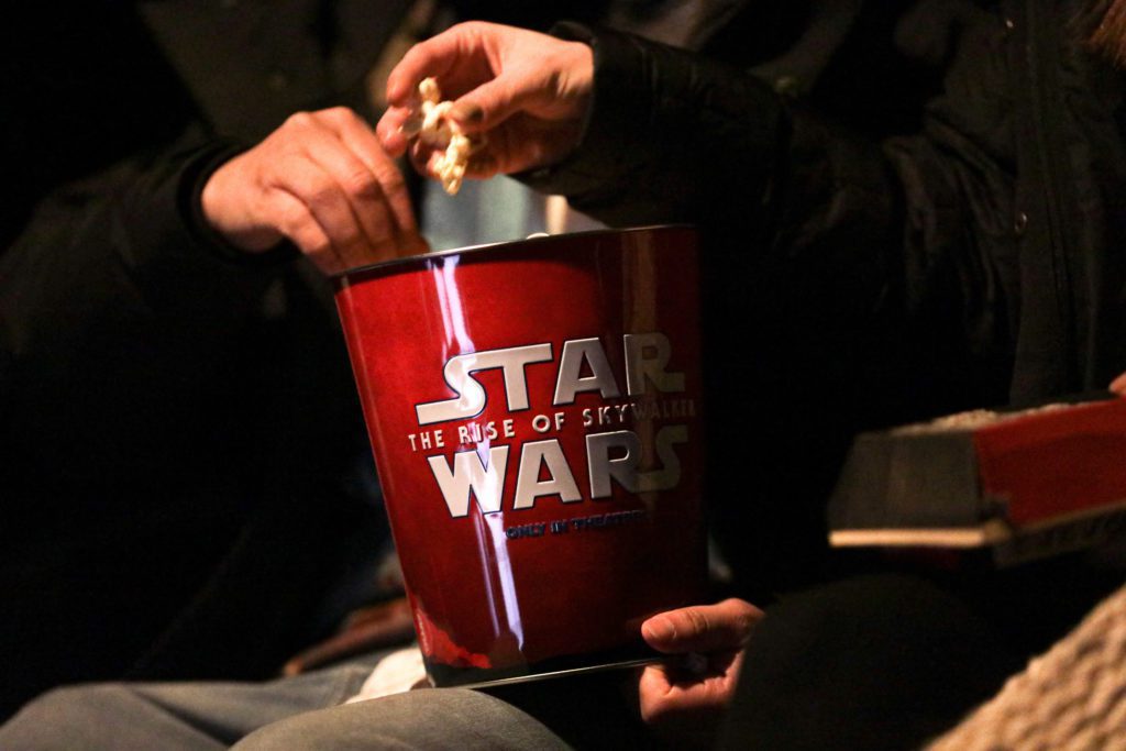Pessoas comendo pipoca de um balde Star Wars: A Ascensão Skywalker no cinema.