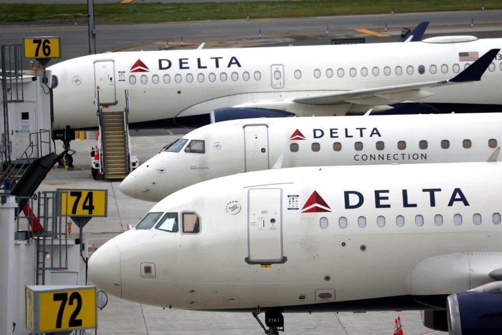 Três jatos Delta brancos parados em fila no aeroporto.