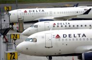 Janelas de três jatos Delta brancos parados em fila no aeroporto.