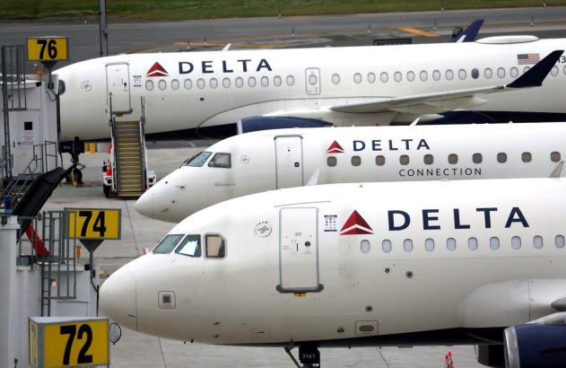 Janelas de três jatos Delta brancos parados em fila no aeroporto.