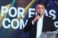 Jair Bolsonaro, de terno, fala em microfone num púlpito, com banner ao fundo.