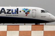Avião da Azul no solo. Fuselagem com logo Azul, mapa do Brasil em mosaico e frase "O Rio de Janeiro continua Azul".