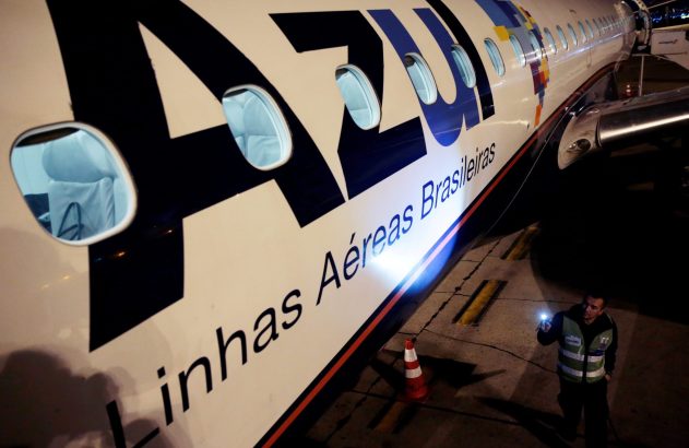 Homem com lanterna inspeciona avião da Azul na pista à noite.