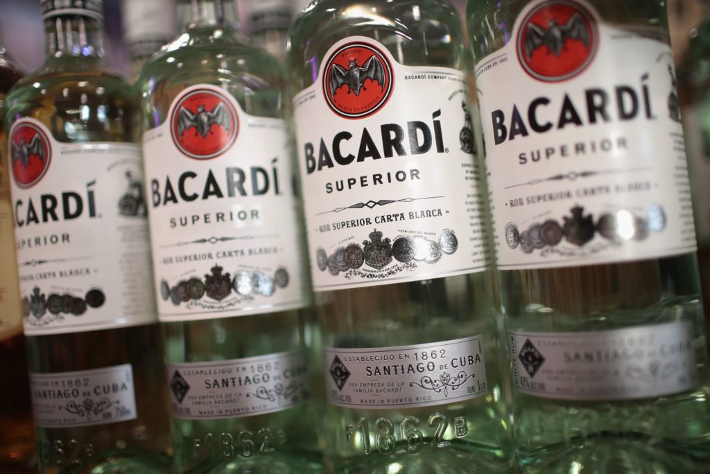 Quatro garrafas de rum Bacardi Superior com rótulos brancos e logo vermelho, alinhadas.