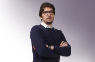 Homem de óculos, barba e suéter azul, com braços cruzados.