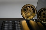 Duas moedas douradas de Bitcoin sobre um laptop, uma com o ano 2018 em destaque.
