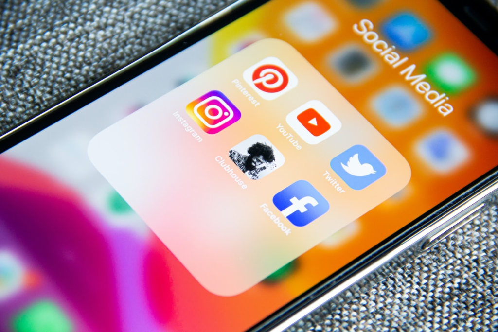 Smartphone exibe pasta "Social Media" com ícones de redes sociais populares.