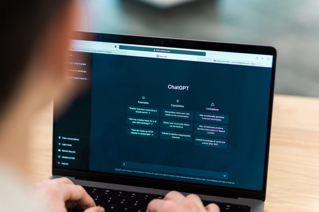 Pessoa digitando em laptop com ChatGPT aberto, exibindo exemplos, capacidades e limitações.