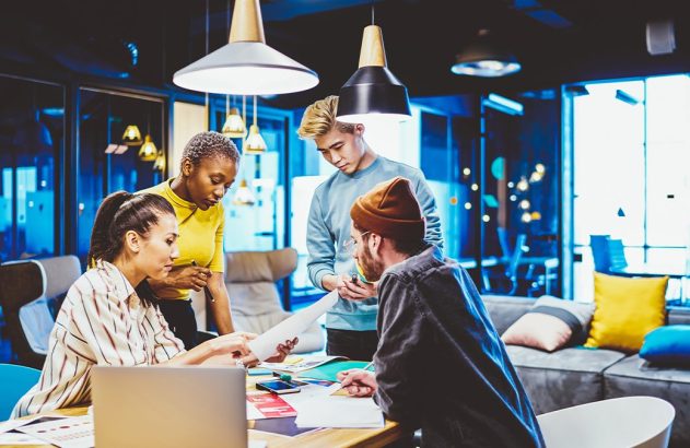 Quatro pessoas em reunião em escritório, discutindo documentos.