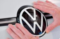 Mãos posicionando o logotipo da Volkswagen em uma superfície branca.