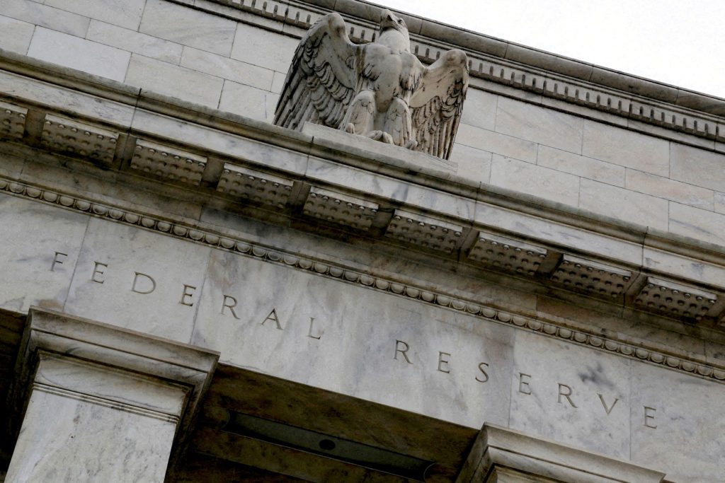 Fachada de pedra do Federal Reserve com inscrição "FEDERAL" e escultura de águia no topo.