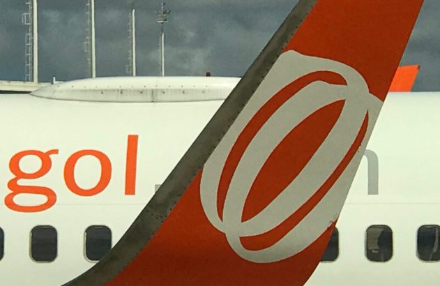 Cauda laranja e branca de avião da GOL, com o logo, parte da palavra 'gol' na fuselagem e janelas.