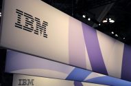 Banners suspensos da IBM com logo listrado em preto e desenhos abstratos em roxo, branco e azul.