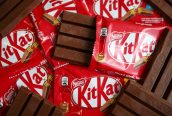 Barras de chocolate Kit Kat: algumas em embalagens vermelhas, uma aberta, e outras desembrulhadas.