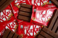 Barras de chocolate Kit Kat: algumas em embalagens vermelhas, uma aberta, e outras desembrulhadas.